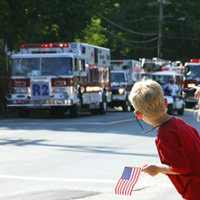 A boy watching a parade of emergency vehicles