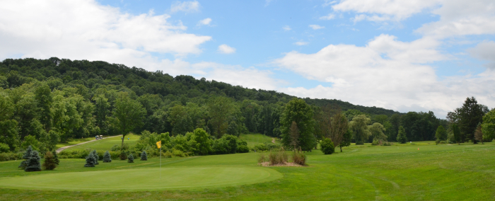 Panoramic view of golf course and tree-covered hills