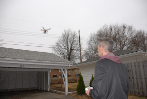 A man flying a small drone near overhead power lines