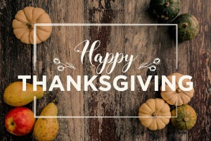 An arrangement of gourds, pears, and apples around the words Happy Thanksgiving